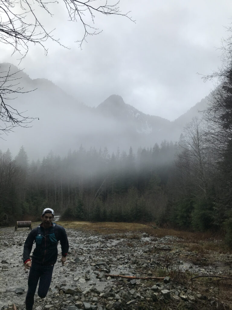 Jacob Haas running on a rocky trail through a misty Lynn Valley, British Columbia